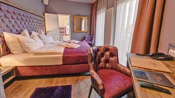 Una habitación de hotel con una cama grande, una silla, un escritorio con teléfono y documentos, y una ventana con cortinas.