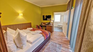 Una habitación de hotel con una cama, un escritorio, un espejo y un armario.