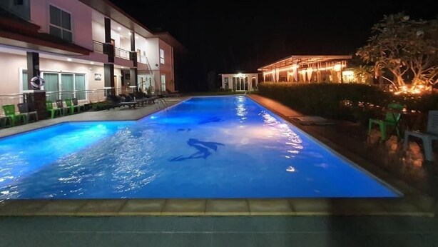 Una piscina dal riflesso blu, circondata da edifici con balconi e zone relax all'aperto.