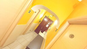 A hallway with yellow walls and a door marked with the number 118. - Hola Roma (Rome)