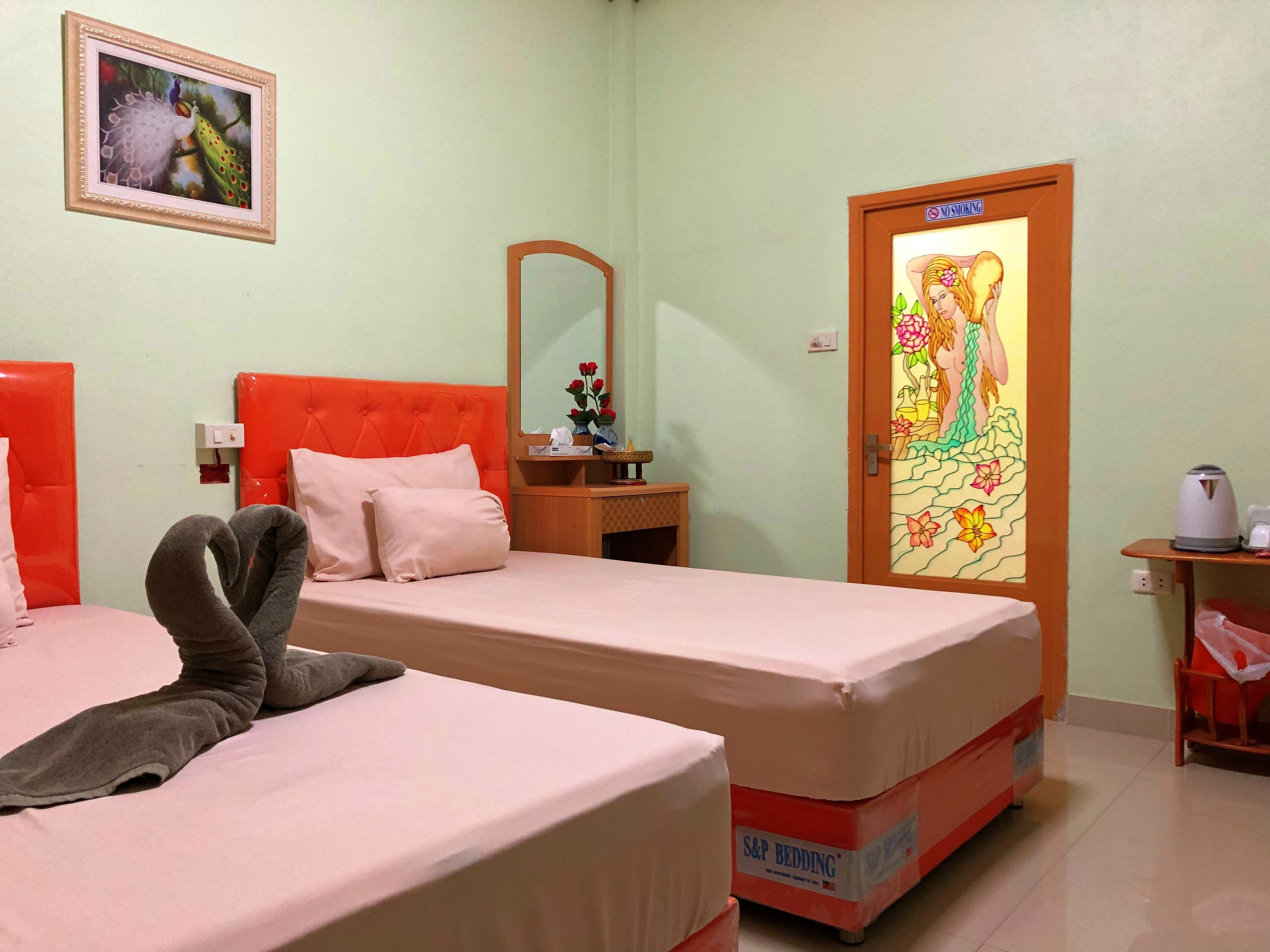 Quarto de hotel com duas camas, um espelho, um quadro e uma porta com decoração floral.