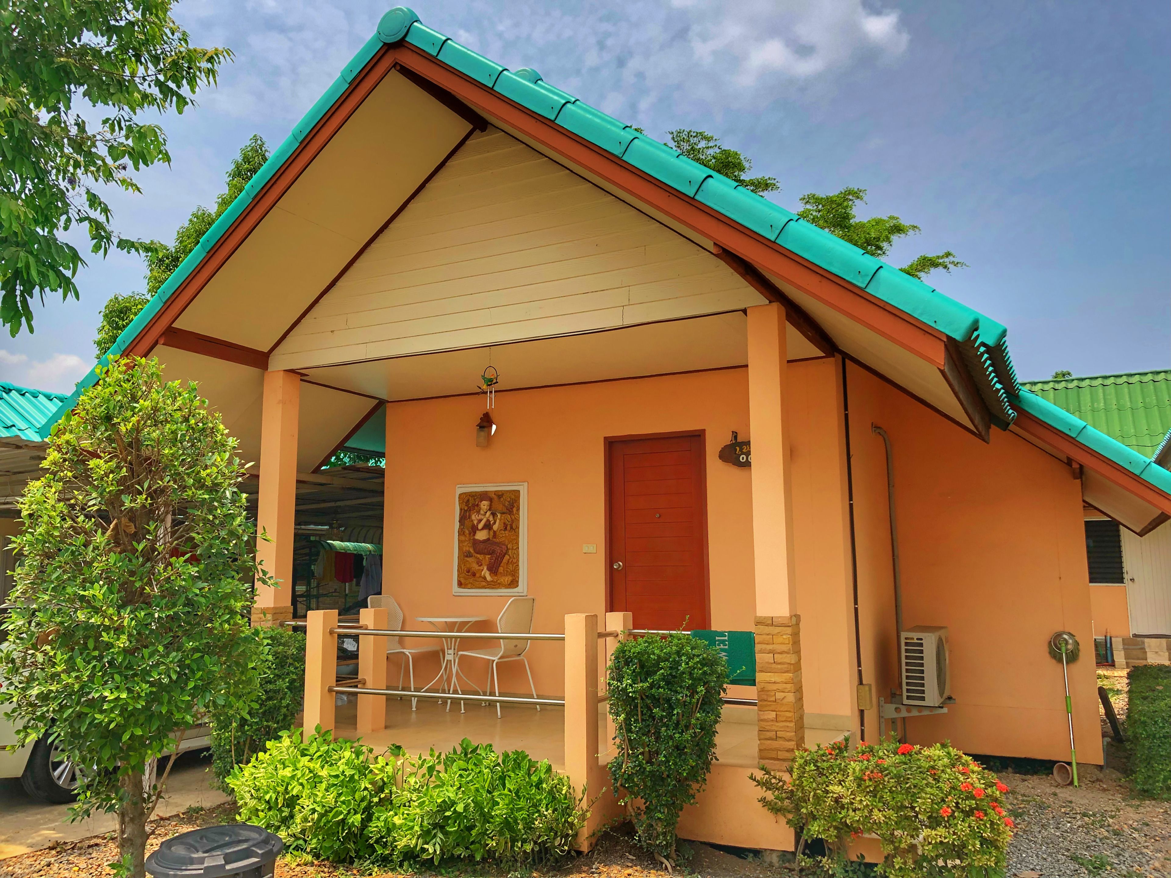 A building with a pitched roof, a front door, and a small porch area with a table and chairs.