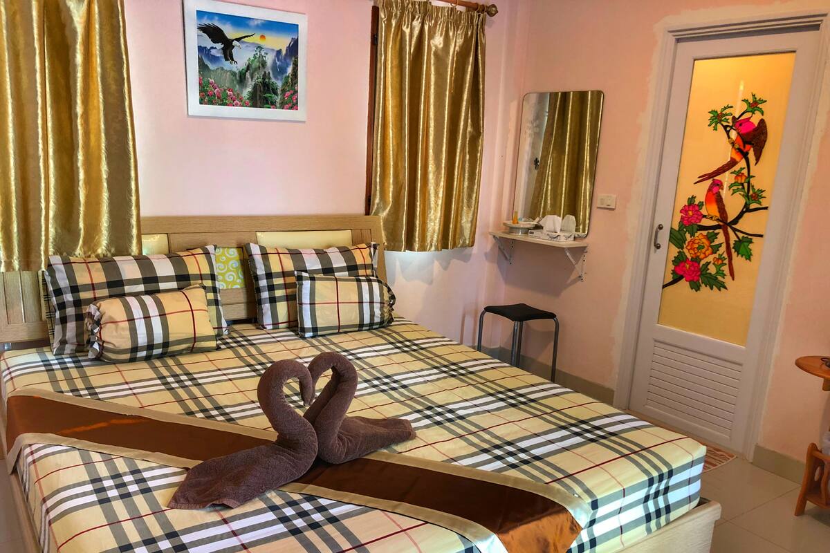 Une chambre d’hôtel avec un lit agrémenté d’une couverture à carreaux, de coussins et d’une décoration en forme de cœur faite de serviettes.