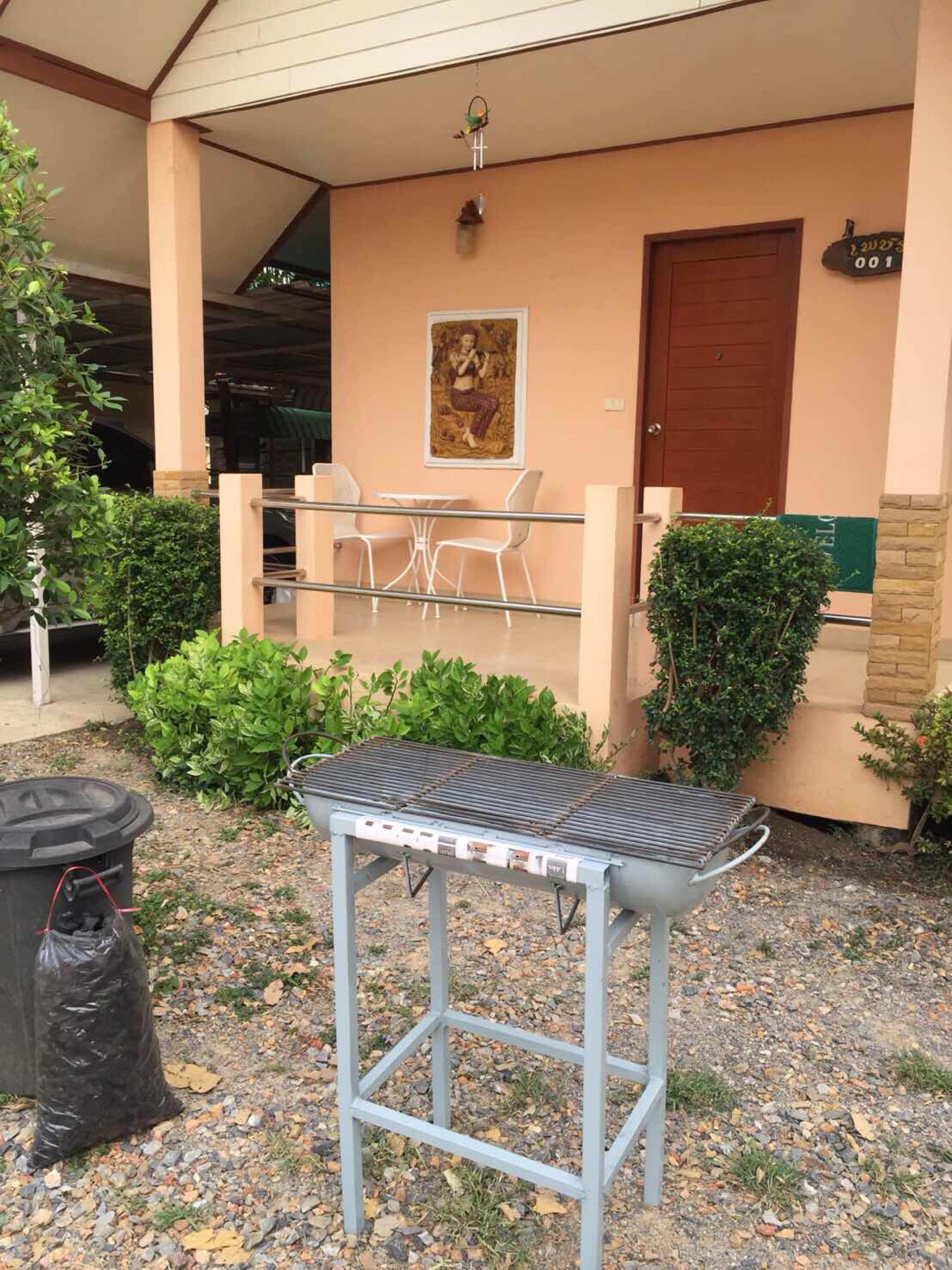 Un área de patio al aire libre con una parrilla, un basurero y una zona de estar con sillas y una mesa.