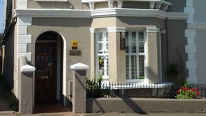 A two-story building with a symmetrical facade, large windows, and a prominent entrance with a door and a small porch. - Gyves Guest House (Eastbourne)