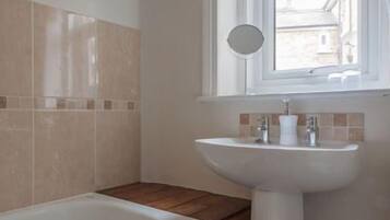 A bathroom with a bathtub, a sink, and a window.