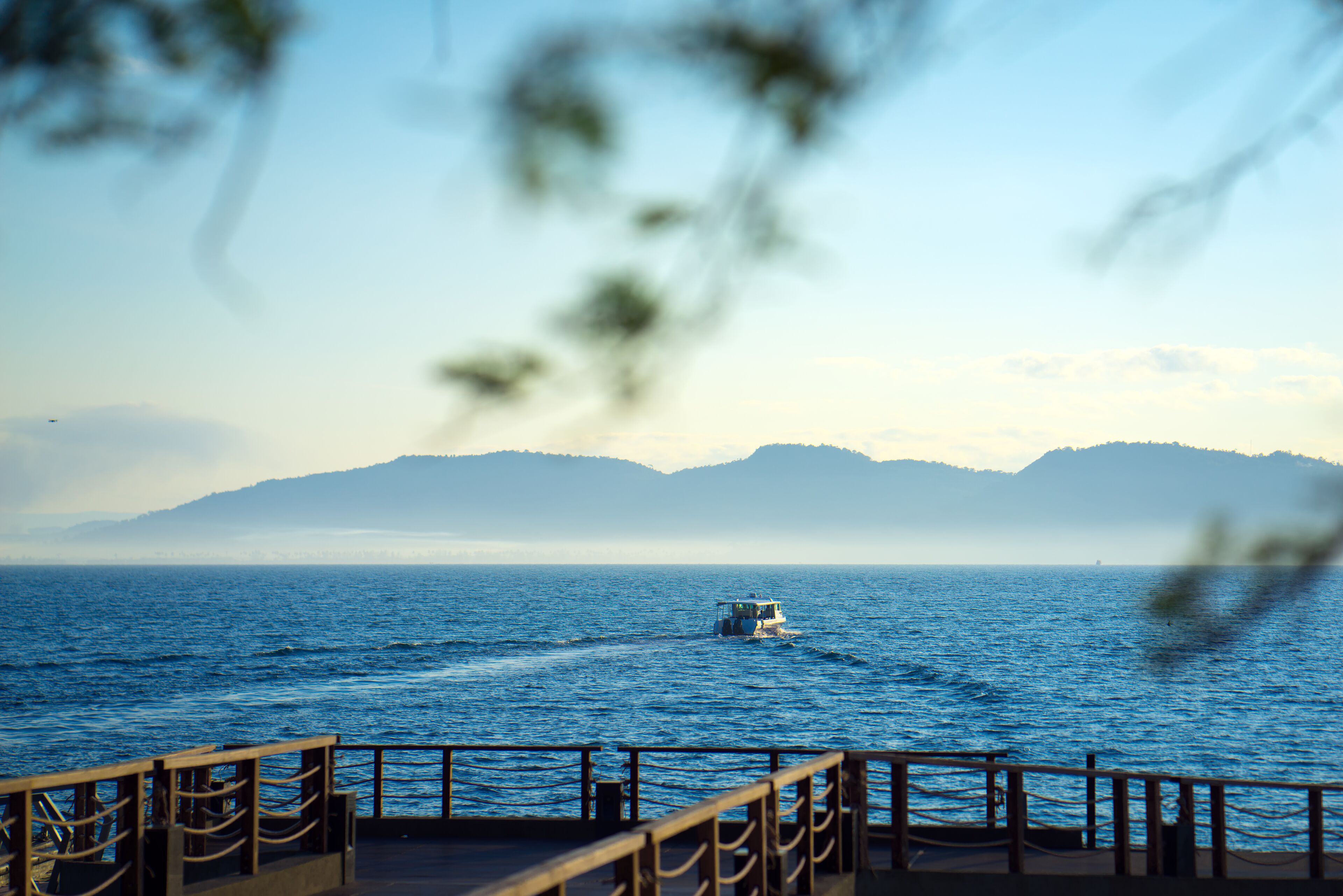 A boat on a calm sea with distant mountains.