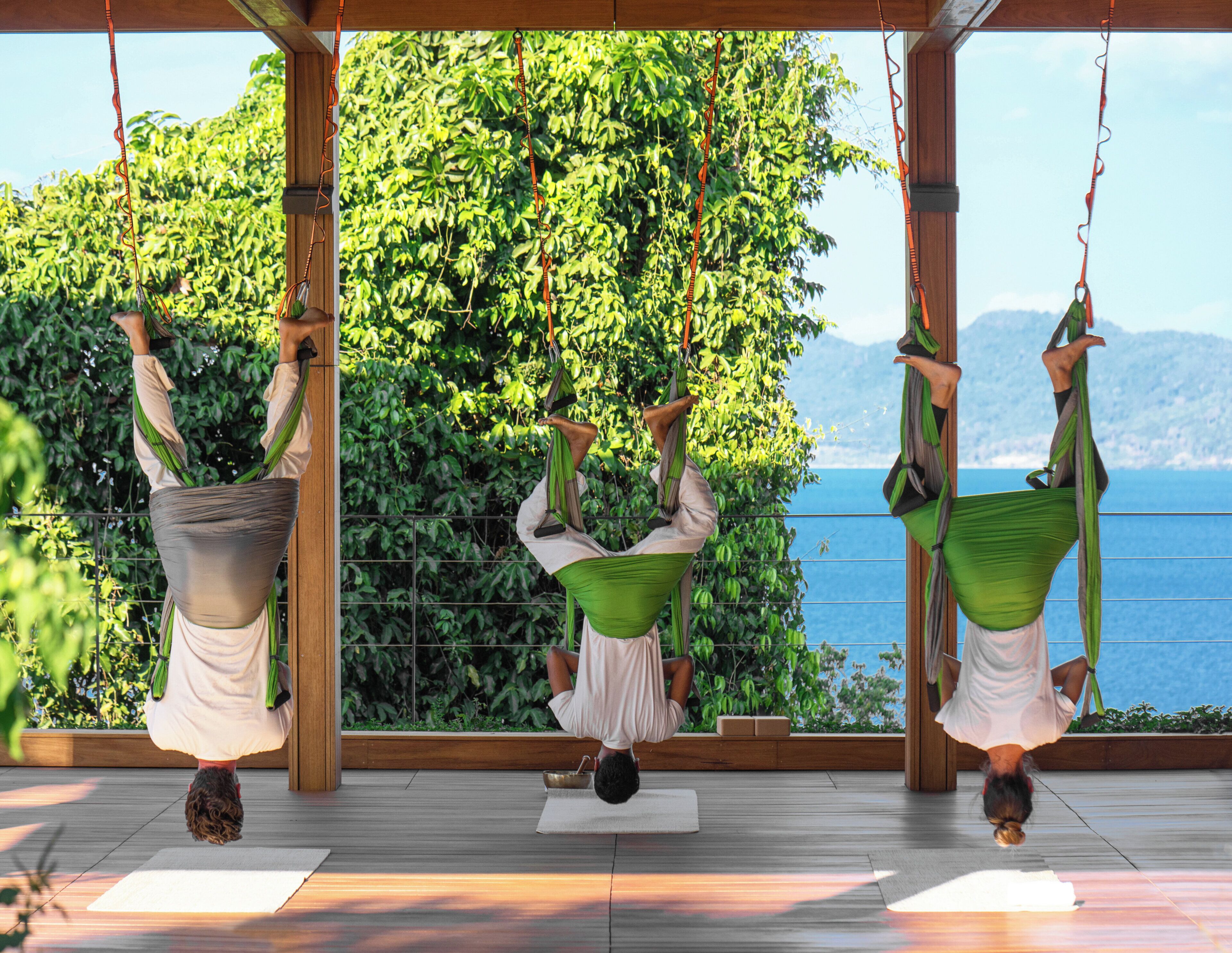 A yoga studio with a view of the sea, featuring wooden floors and a large window.