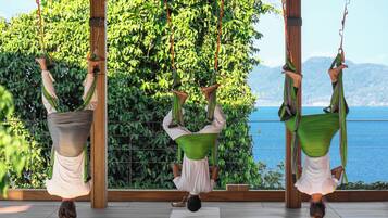 A yoga studio with a view of the sea, featuring wooden floors and a large window.