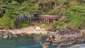 Une station balnéaire dotée d’une plage, d’une piscine et d’un bâtiment aux grandes fenêtres donnant sur la mer.