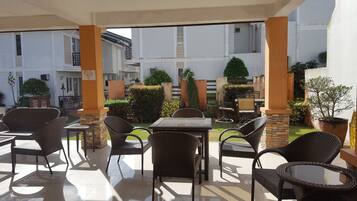 An outdoor patio area with wicker furniture, a tiled floor, and a view of the building's exterior.
