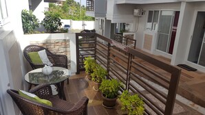 A balcony with wicker furniture, potted plants, and a glass table. - 2 Bedroom Villa by AP at Tagaytay Hampton Villa (Tagaytay)
