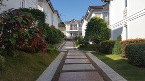 A residential street with houses on both sides, a central pathway, and well-maintained greenery. - 2 Bedroom Villa by AP at Tagaytay Hampton Villa (Tagaytay)