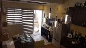 A modern kitchen with a glass-top island, stainless steel appliances, and a sliding glass door to the patio. - 2 Bedroom Villa by AP at Tagaytay Hampton Villa (Tagaytay)