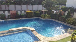 A swimming pool with a stone border and a small water feature. - 2 Bedroom Villa by AP at Tagaytay Hampton Villa (Tagaytay)