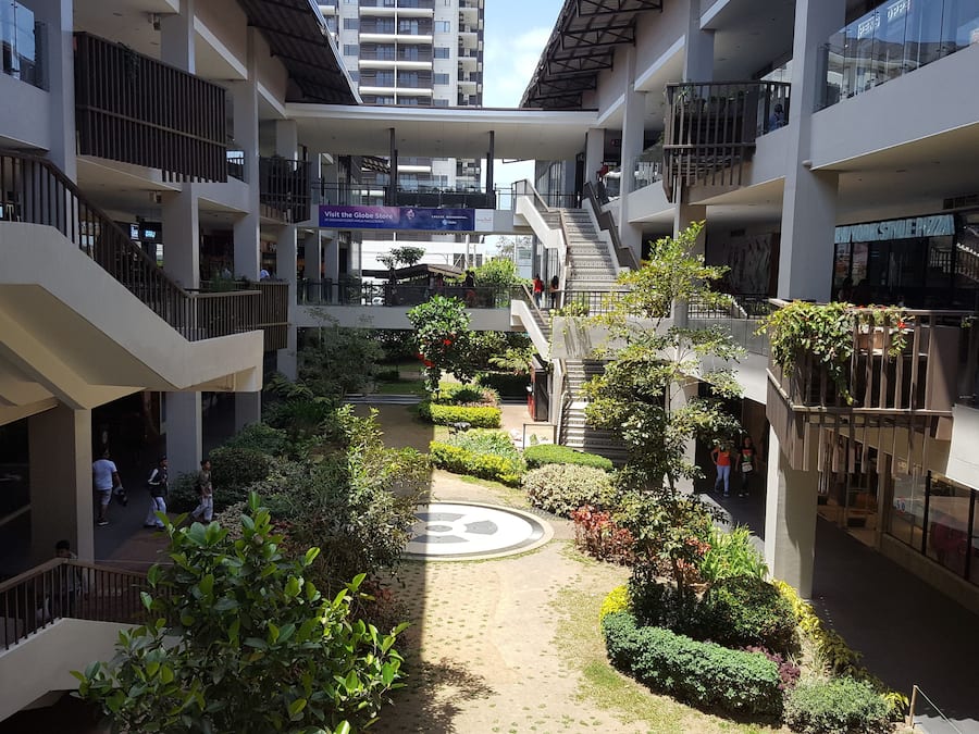 En fleretages atriumgård med en central have, balkoner og butikker.