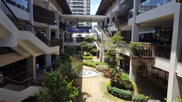 A multi-level atrium with a central garden, balconies, and retail stores.