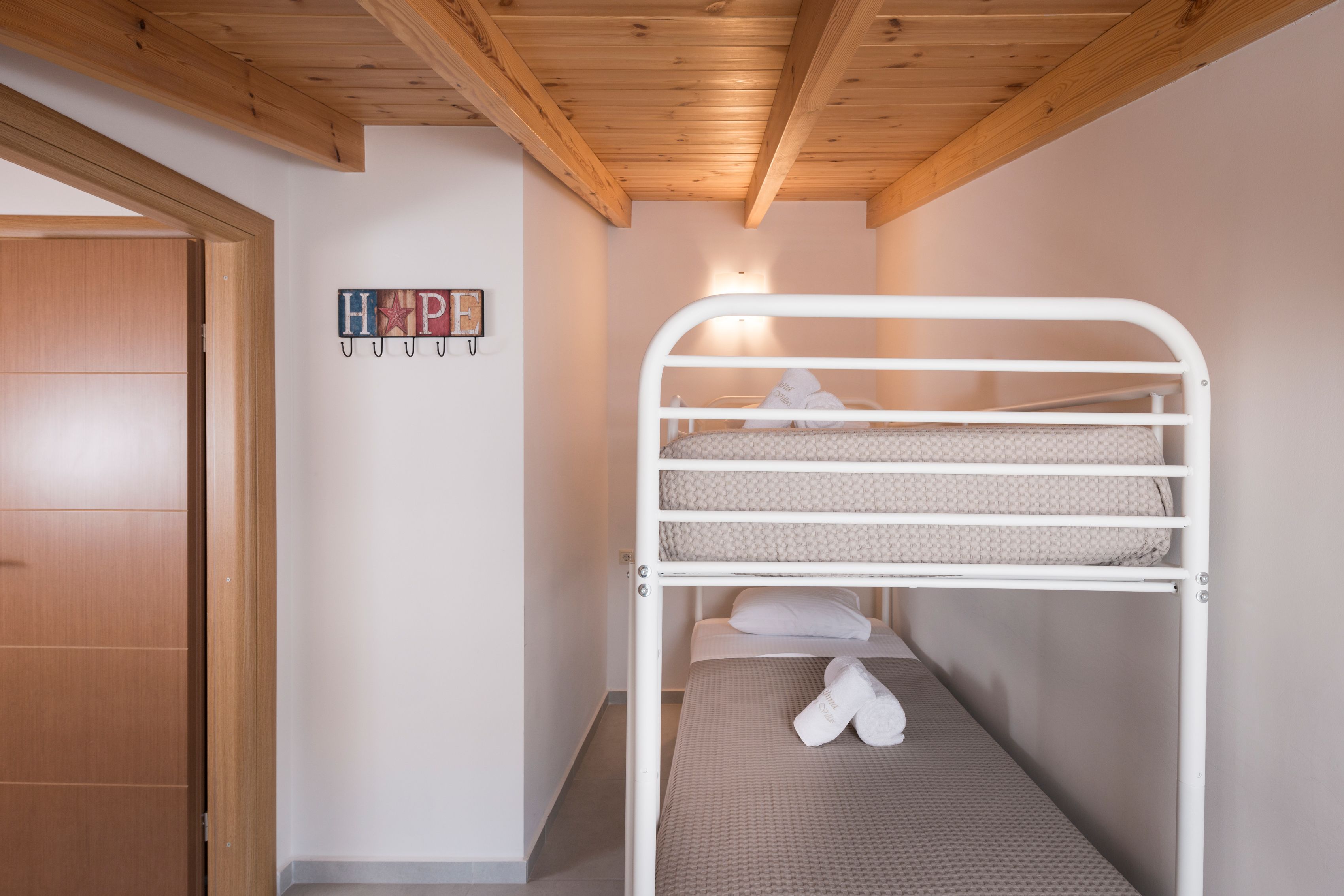 Ein Stockbett mit Holzbalkendecke und einer Tür zur Linke.