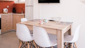 A modern kitchen with wooden cabinets, a built-in oven, and a flat-screen TV mounted on the wall. - Athina Apartments (Platanias)