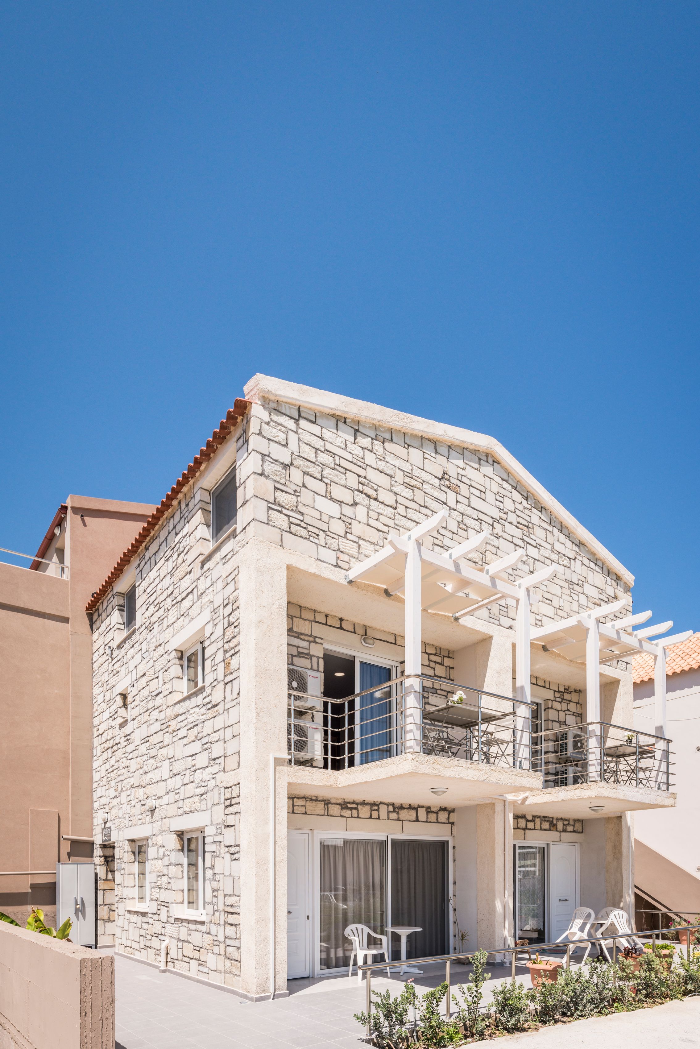 A two-story stone building with a balcony and outdoor seating area.
