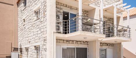 A two-story stone building with a balcony and outdoor seating area.