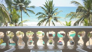 Un balcon avec vue sur la plage et les palmiers.