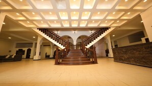 Un magnifique escalier en bois, avec une rampe, mène à un palier qui donne sur un vaste hall d’entrée doté d’un haut plafond et d’un éclairage encastré.