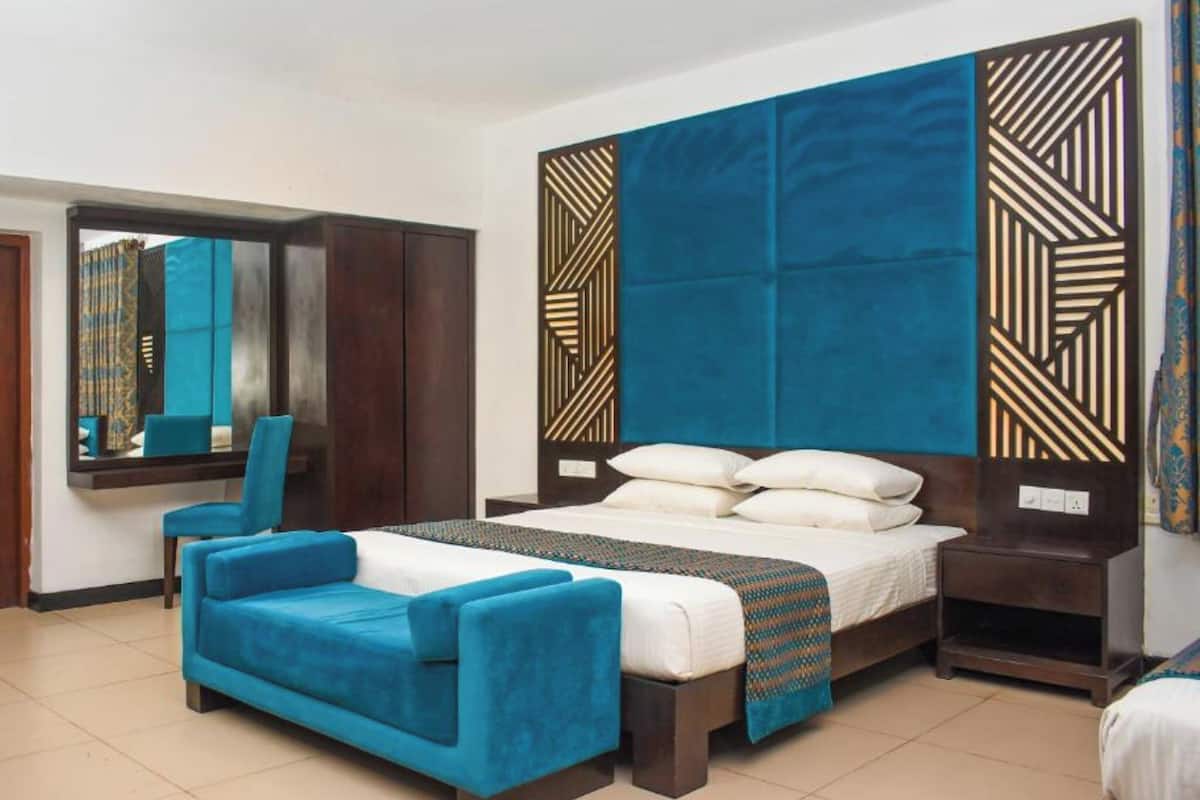 Una habitación de hotel con una cama grande, un sofá, un espejo y un armario.