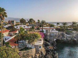 Un pueblo costero con edificios blancos, una torre de piedra y vista al mar.