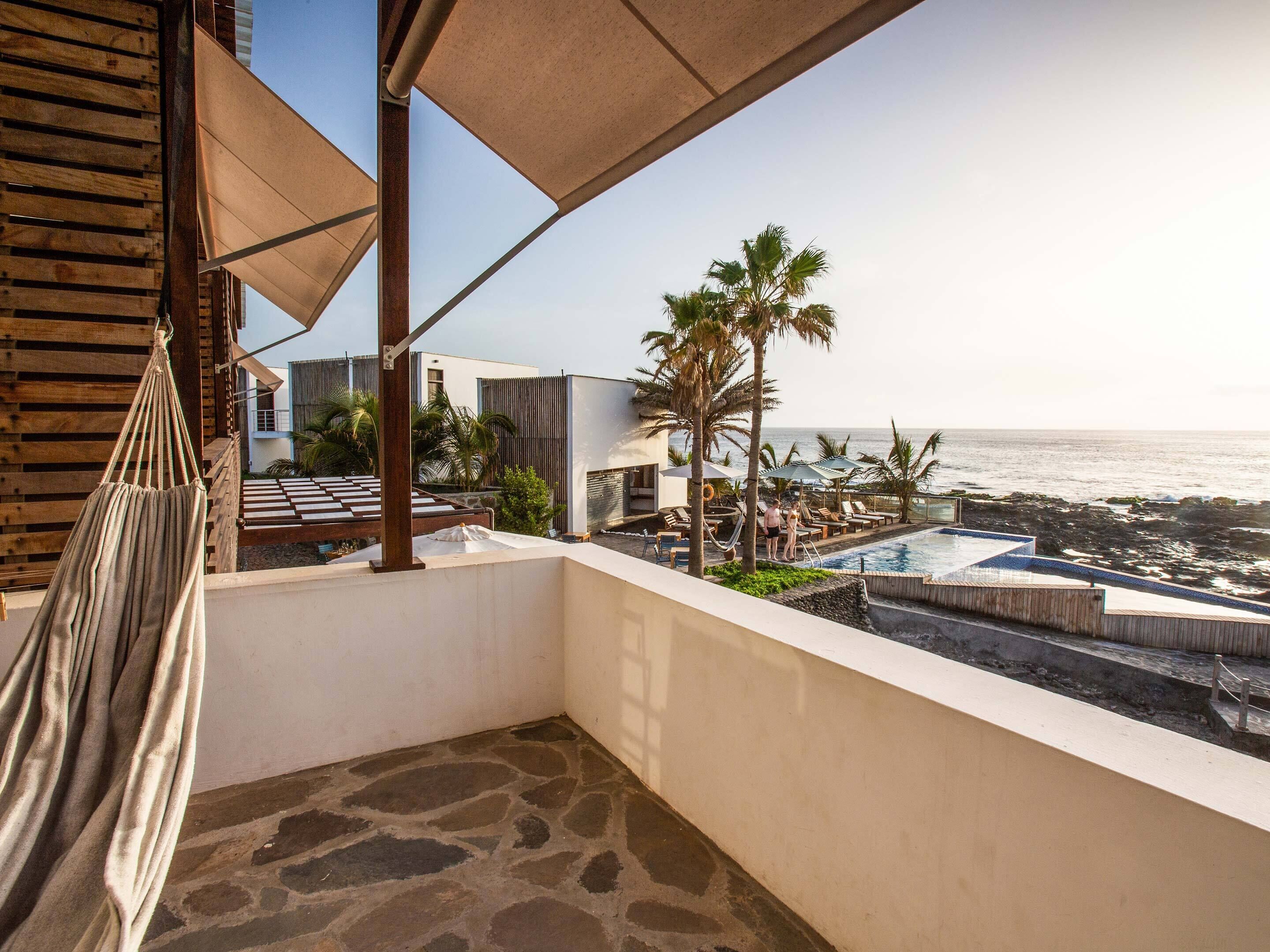 Un balcone con un'amaca, una piscina e vista sull'oceano.