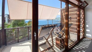 Un balcone con vista sul mare, mobili in legno e un ombrellone grande.