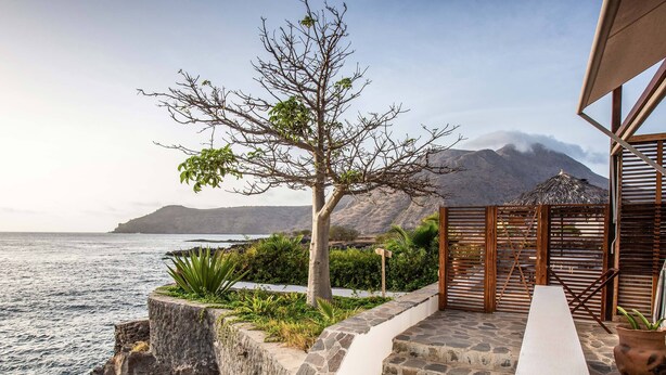 Una proprietà costiera con una scala in pietra che conduce a un pontile in legno con vista sul mare.