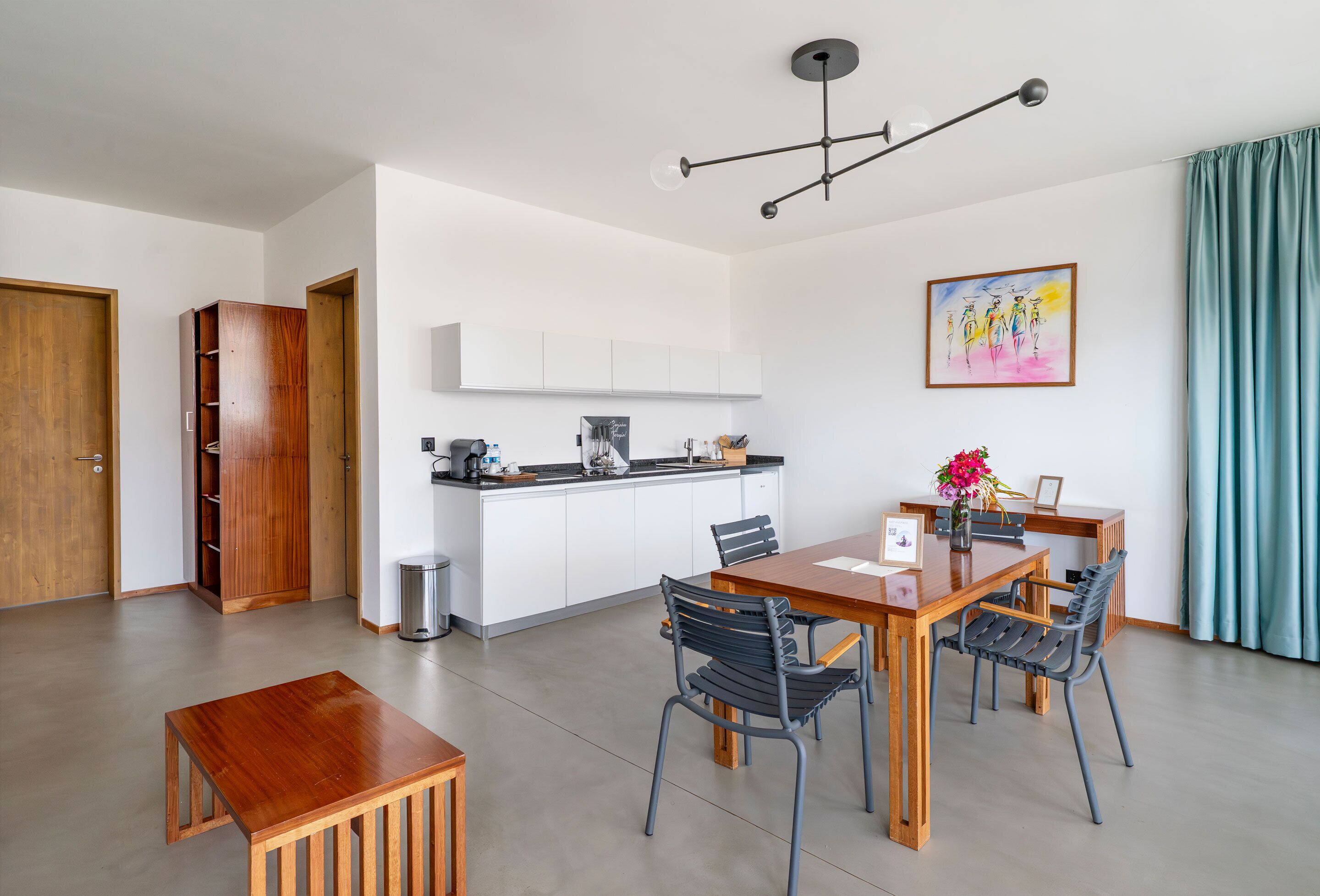 Una cocina moderna con armarios blancos, una mesa de comedor con cuatro sillas y una lámpara colgante.