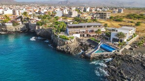 Una località balneare con piscina, scogliere rocciose e vista sul paese.