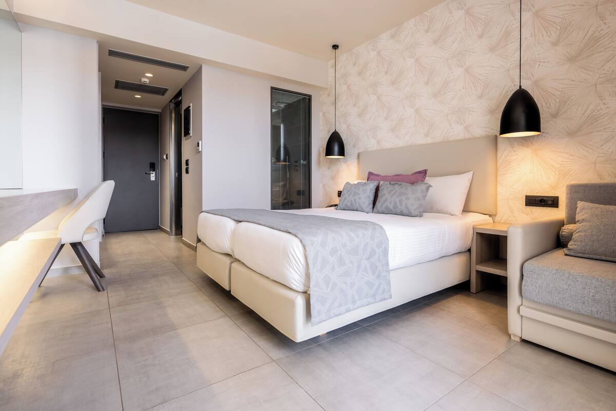 A modern bedroom with a large bed, bedside tables, a desk, and a chair.