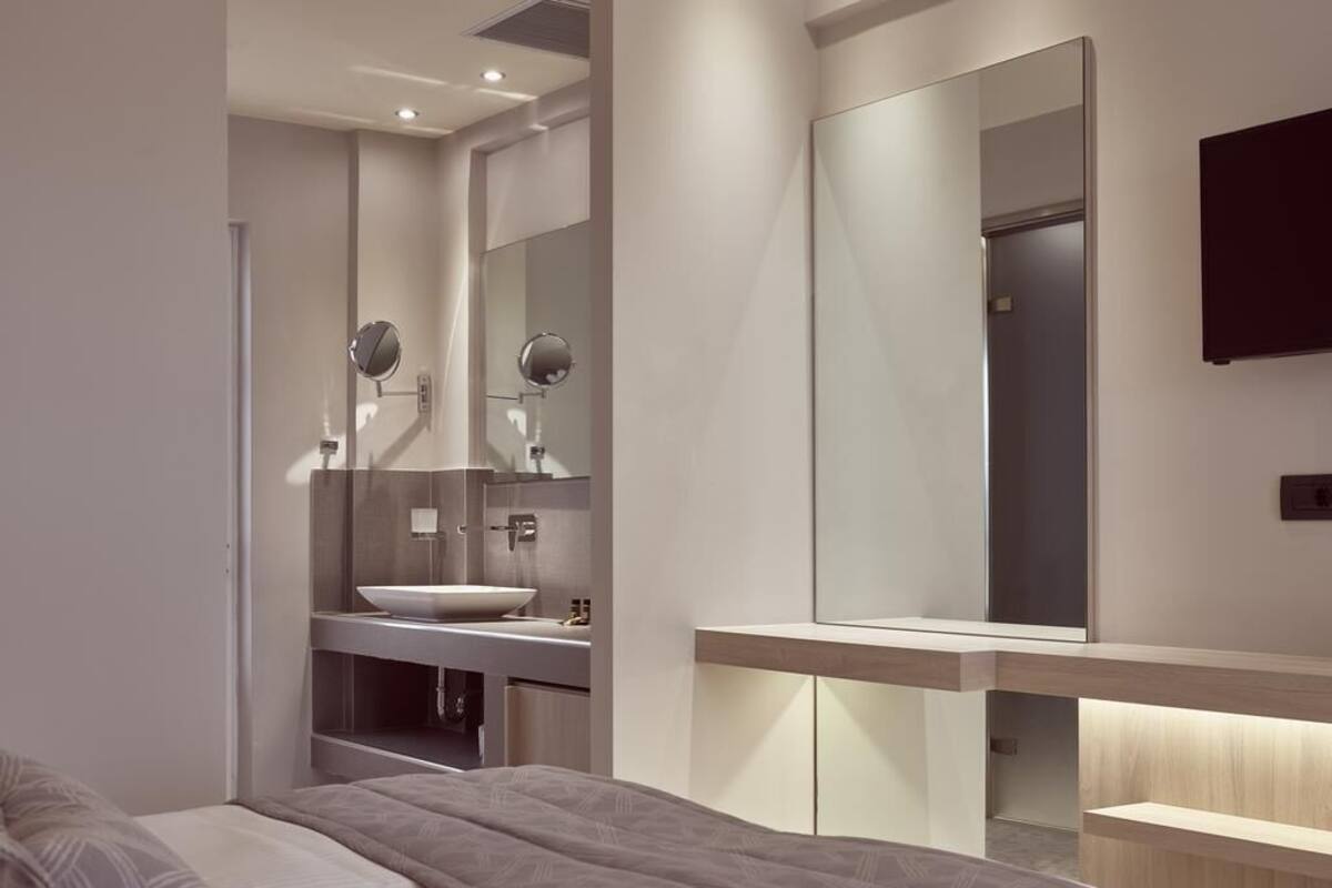 A modern bedroom with a large bed, a built-in vanity with a mirror, and a wall-mounted TV.
