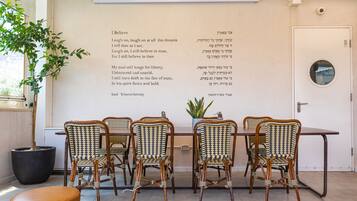 Un comedor con una mesa y cuatro sillas de mimbre, una planta en maceta y una pared con texto.