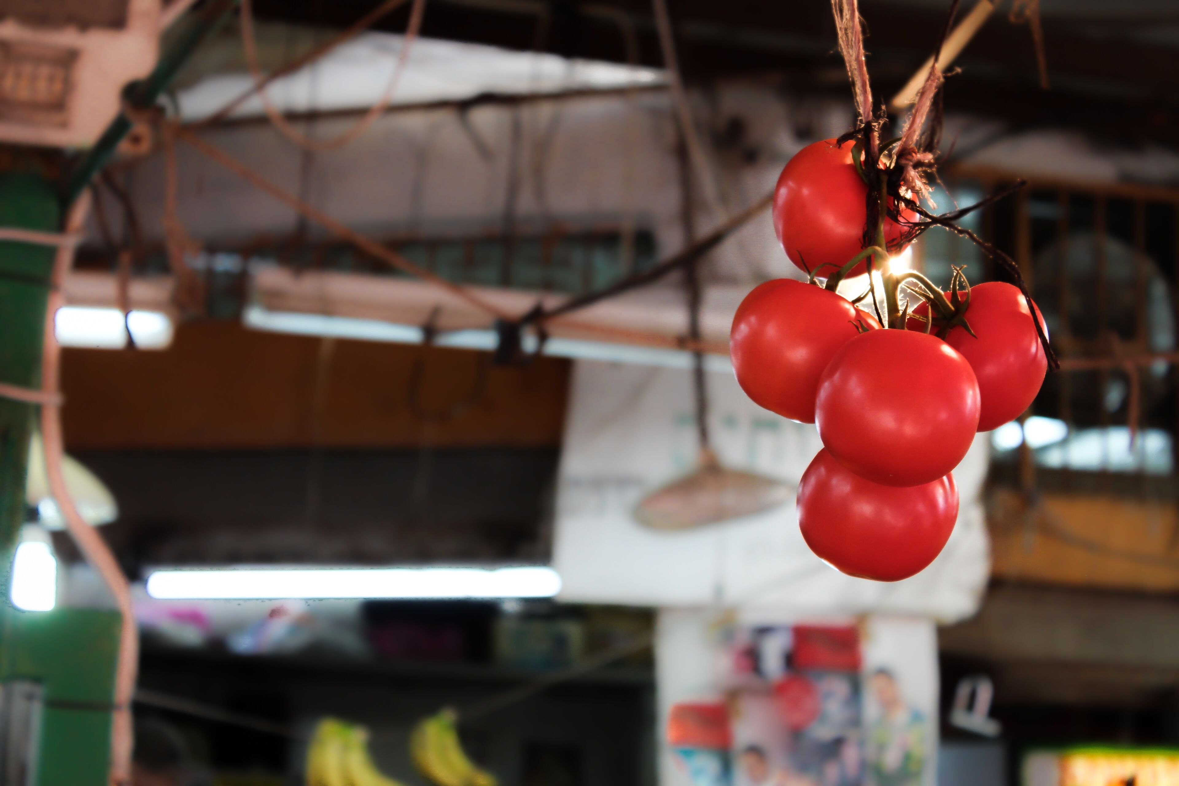 Viele rote Tomaten hängen an einem Zweig auf einem Markt.