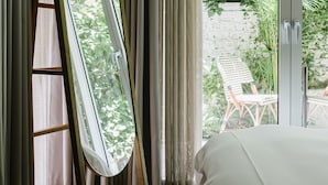 Un dormitorio con un ventanal grande, una cama y un espejo apoyado contra la pared.