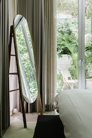 Una camera da letto con un'ampia finestra, un letto e uno specchio appoggiato al muro.