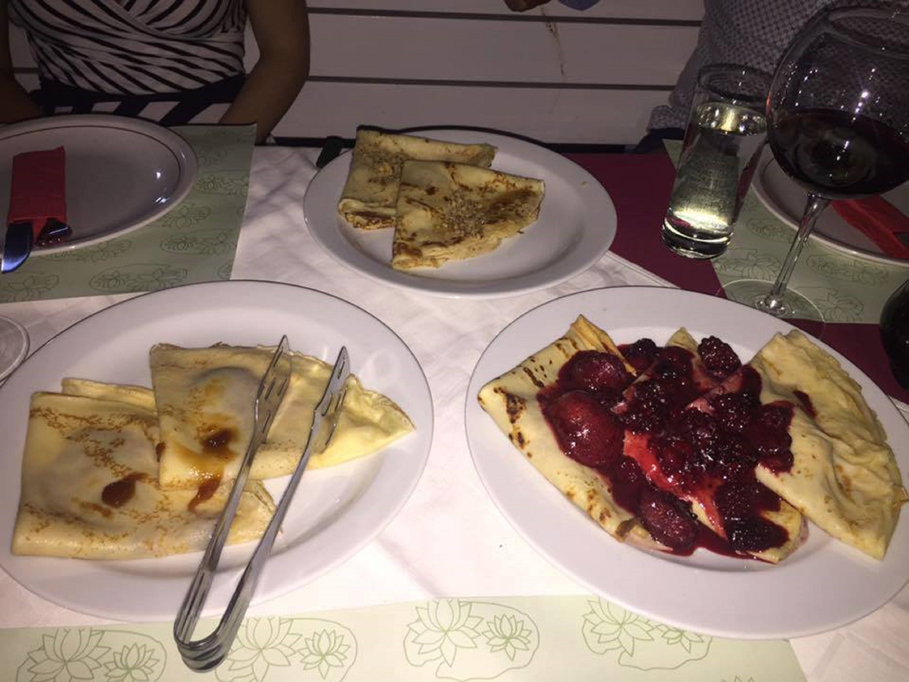 Een tafel met borden eten, waaronder pannenkoeken en een dessert met bessen.