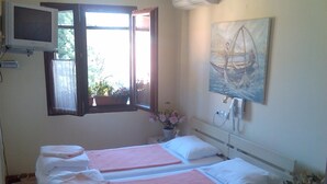 Een hotelkamer met twee bedden, een aan de muur bevestigde televisie, een schilderij en een telefoon.