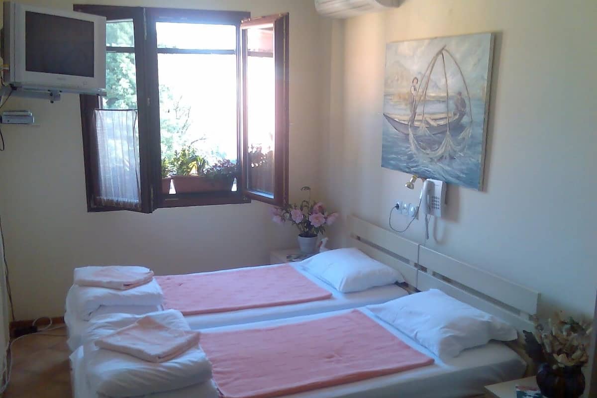 Una camera d'albergo con due letti, una TV a parete, un quadro e un telefono.