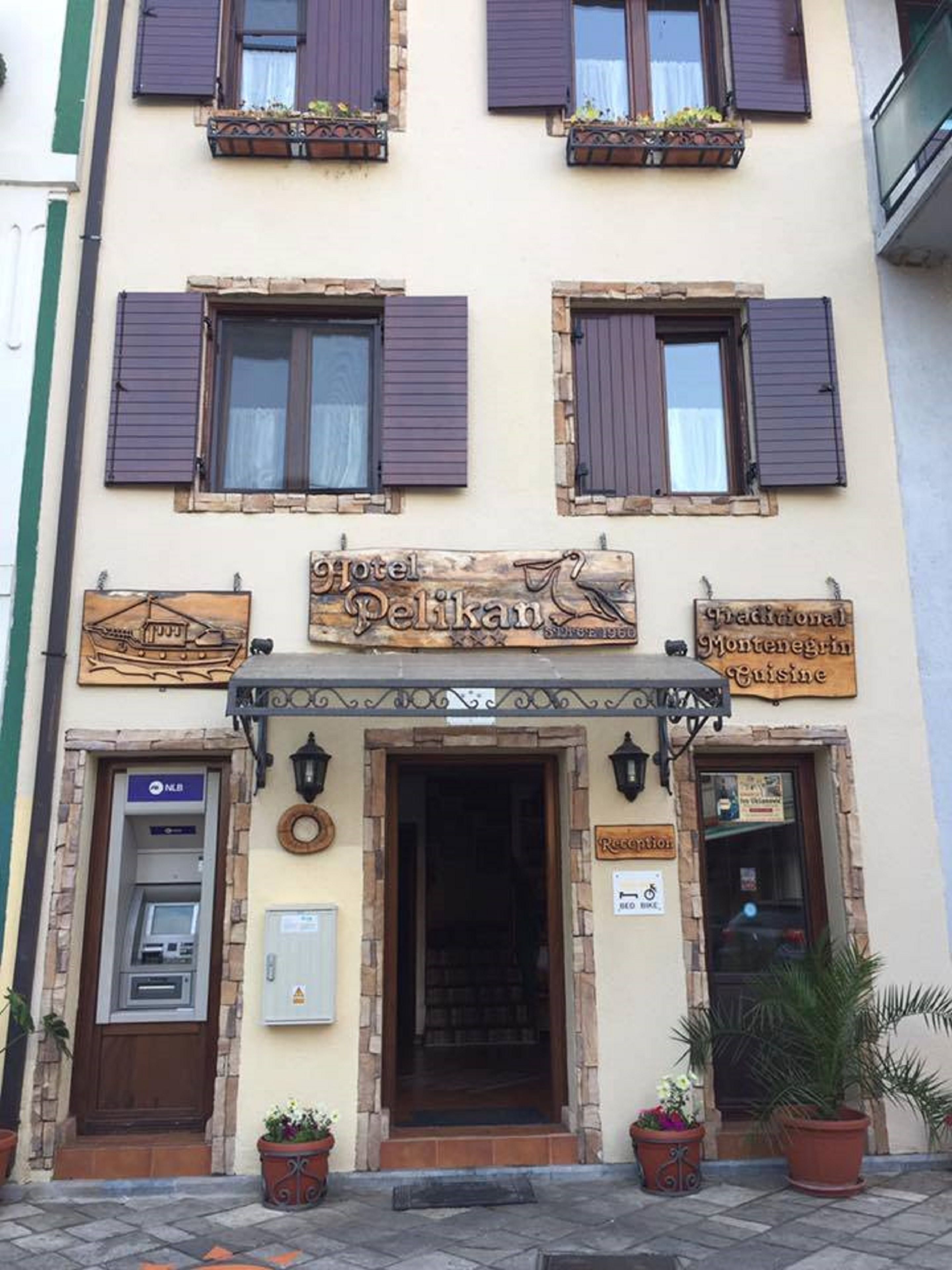 A hotel named "Hotel Pelikan" with a traditional facade, a reception desk, and a sign indicating Montenegrin cuisine.