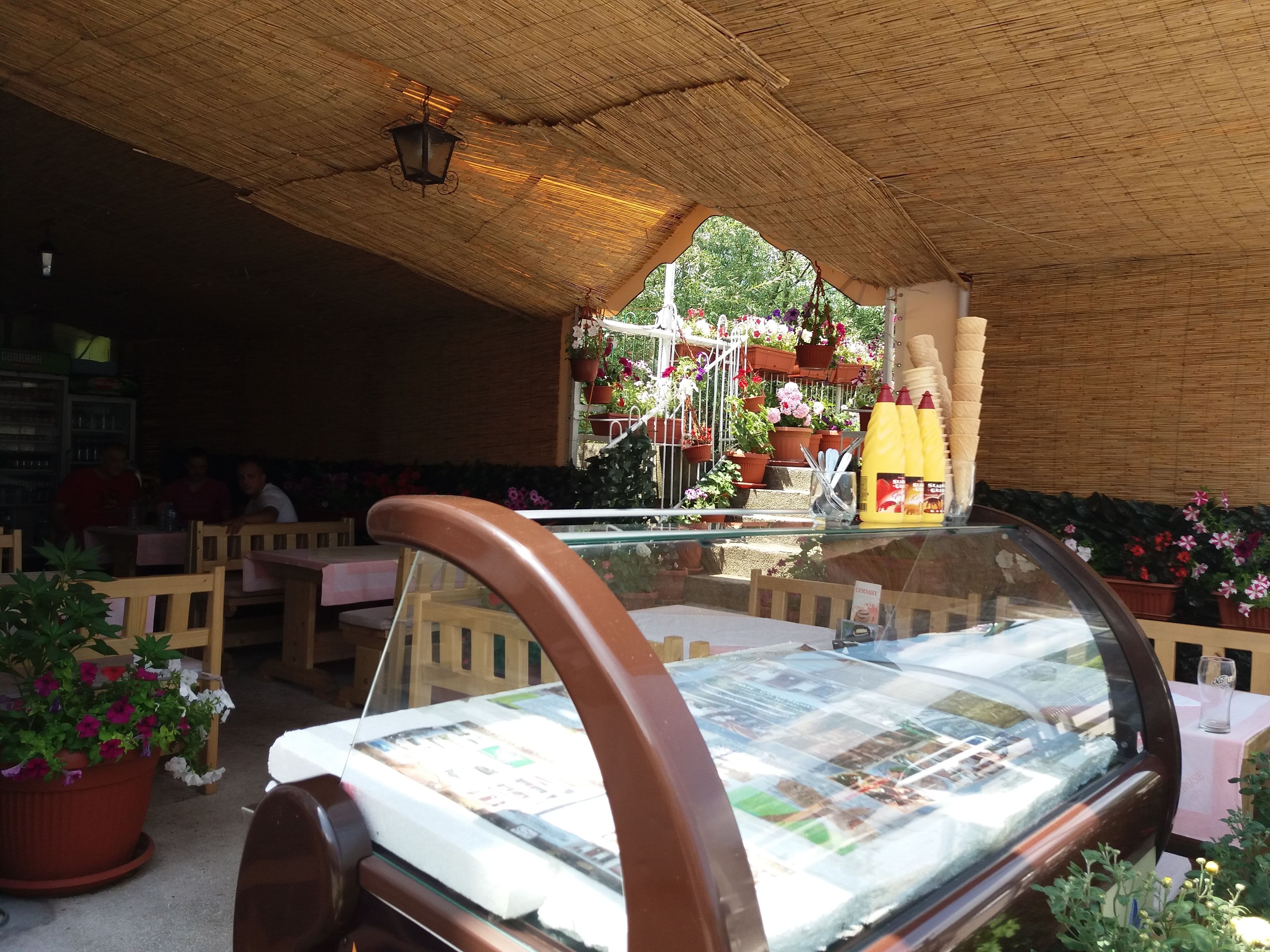 Un restaurante con mobiliario de madera, una mesa de vidrio y plantas en macetas.