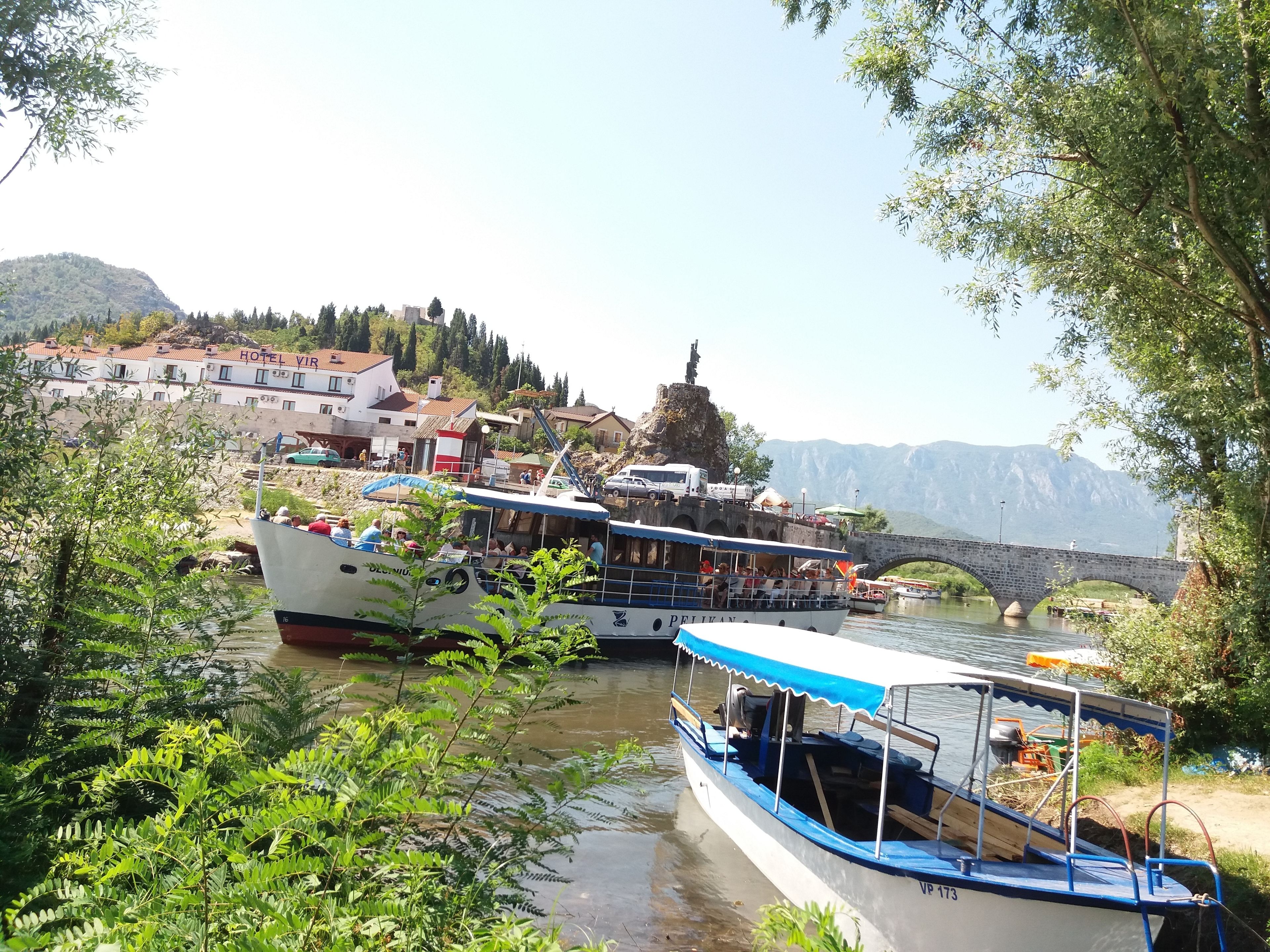 A riverfront area with boats docked, a bridge, and a hotel named "HOTEL VIRGIN" in the background.