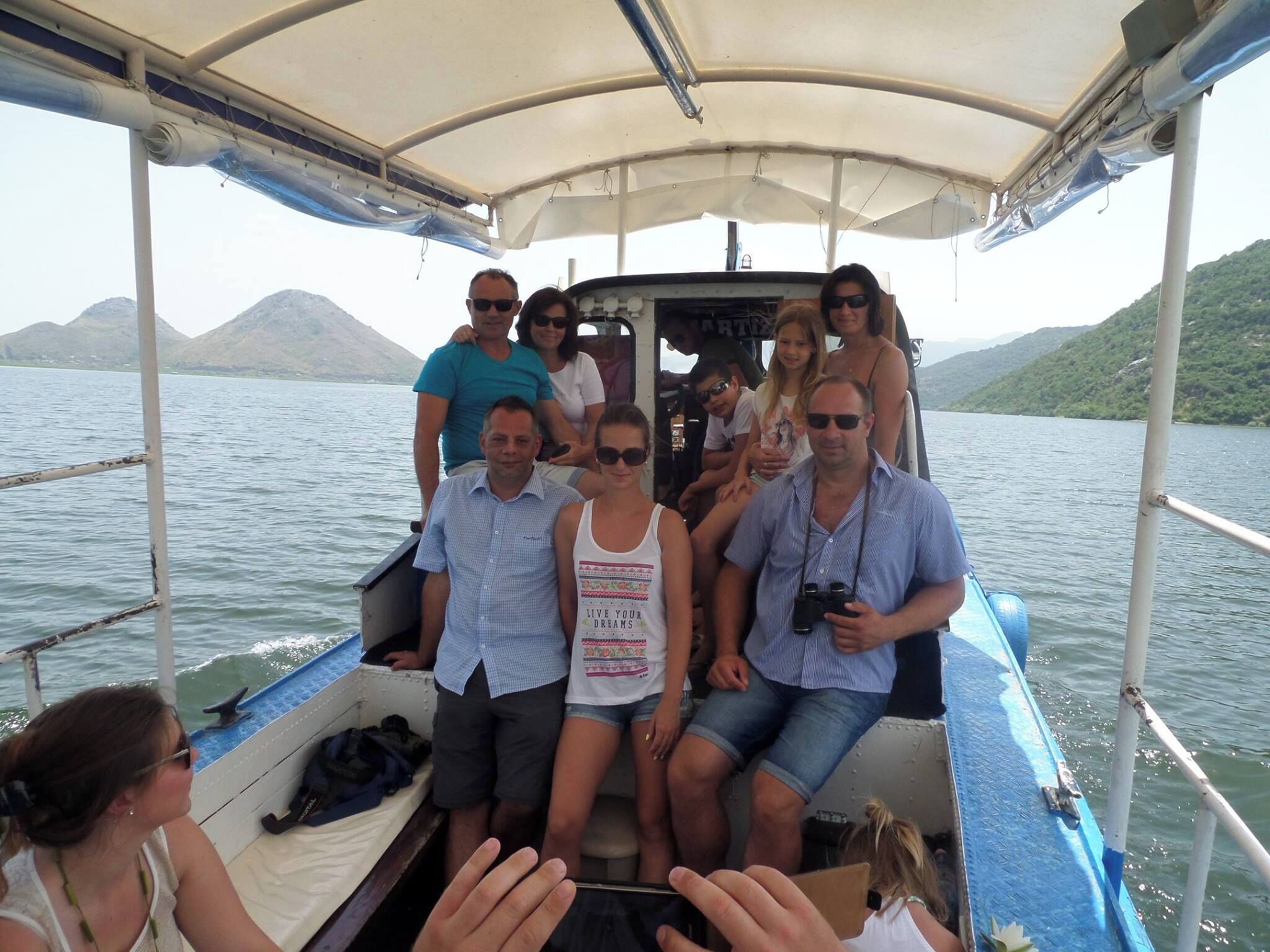 Un grupo de personas en un bote con toldo, rodeado de agua y colinas.