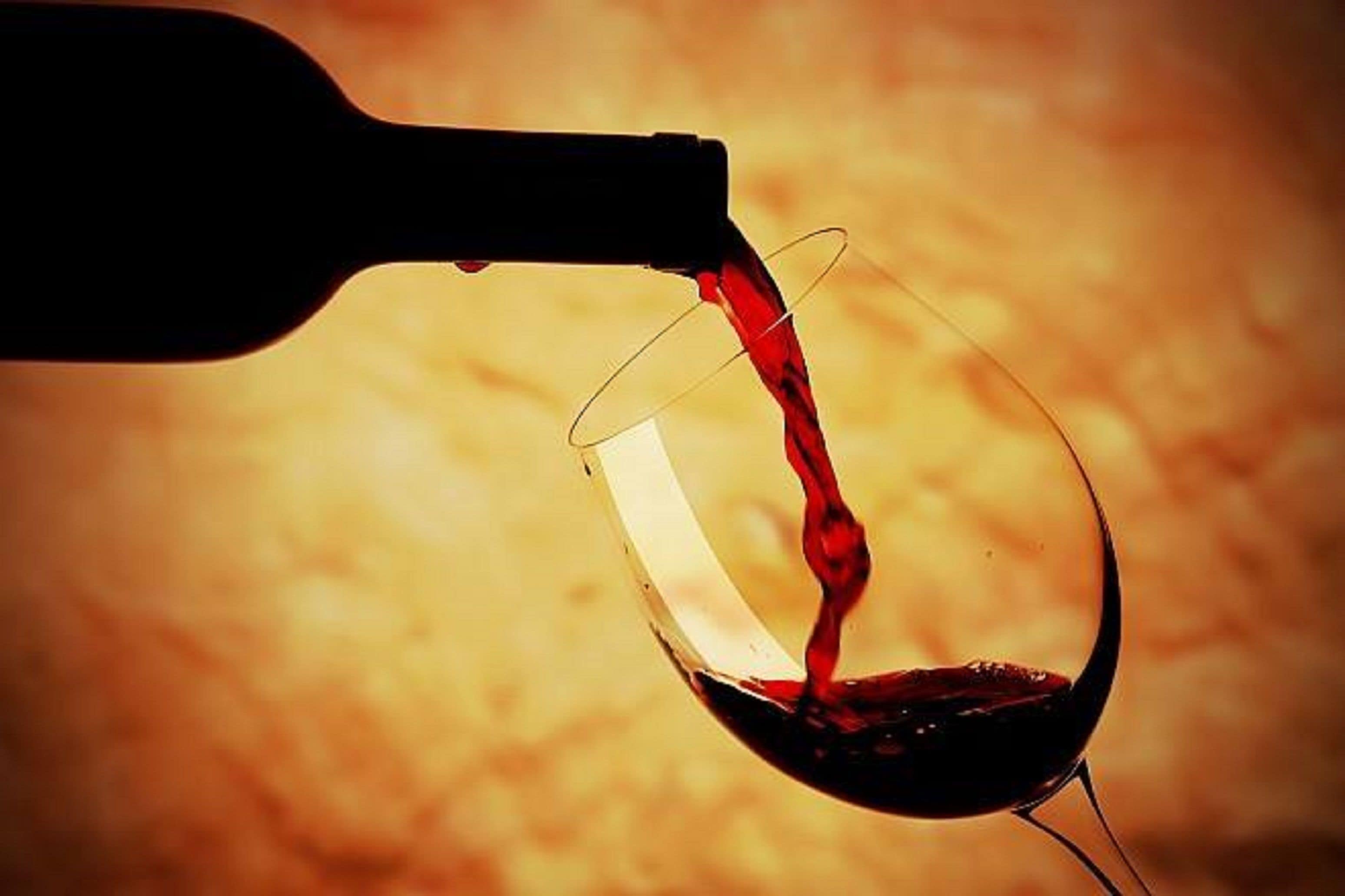 Una botella de vino vertiendo vino en una copa.