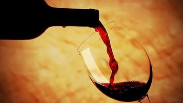 Una botella de vino vertiendo vino en una copa.