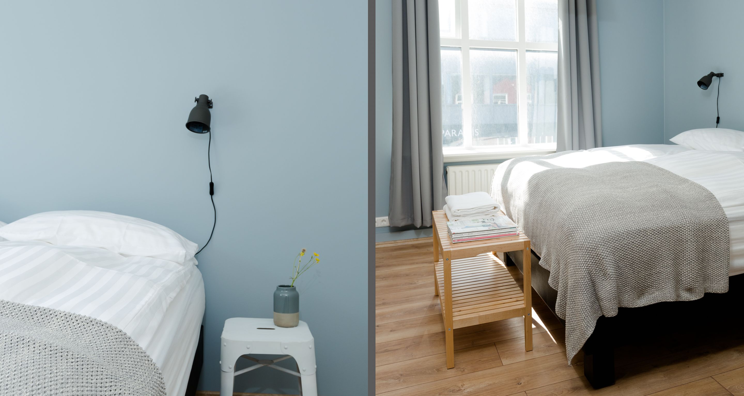 Un dormitorio con dos camas, una mesita de noche de madera, una ventana con cortinas y una lámpara fijada a la pared.